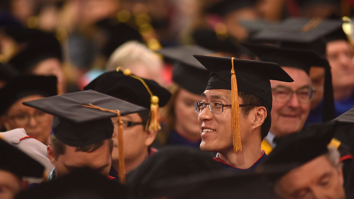 Student with other graduates in regalia looking to side