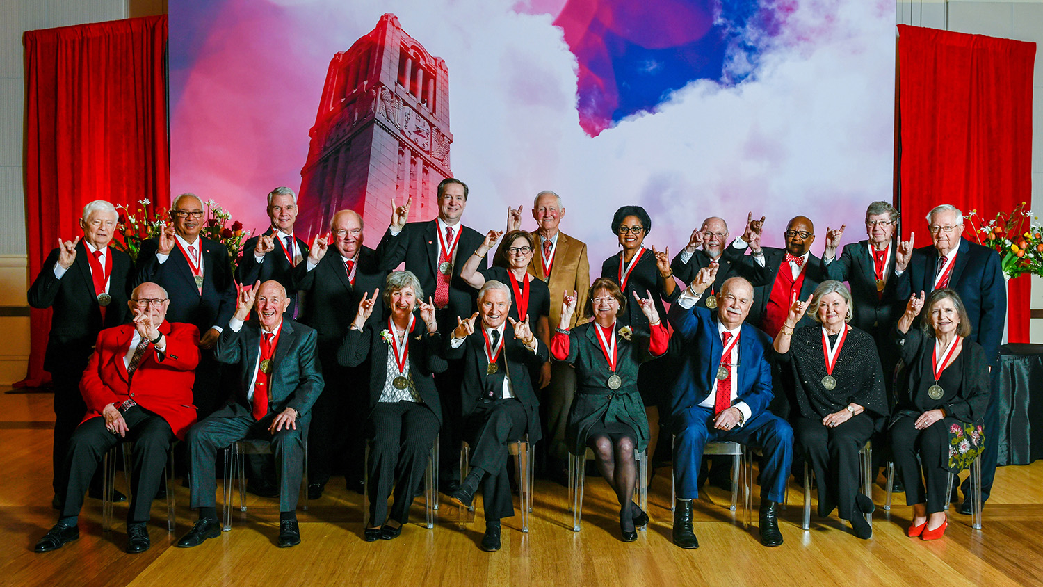 Group of Watauga Medal winners giving Wolfpack sign at dinner event.