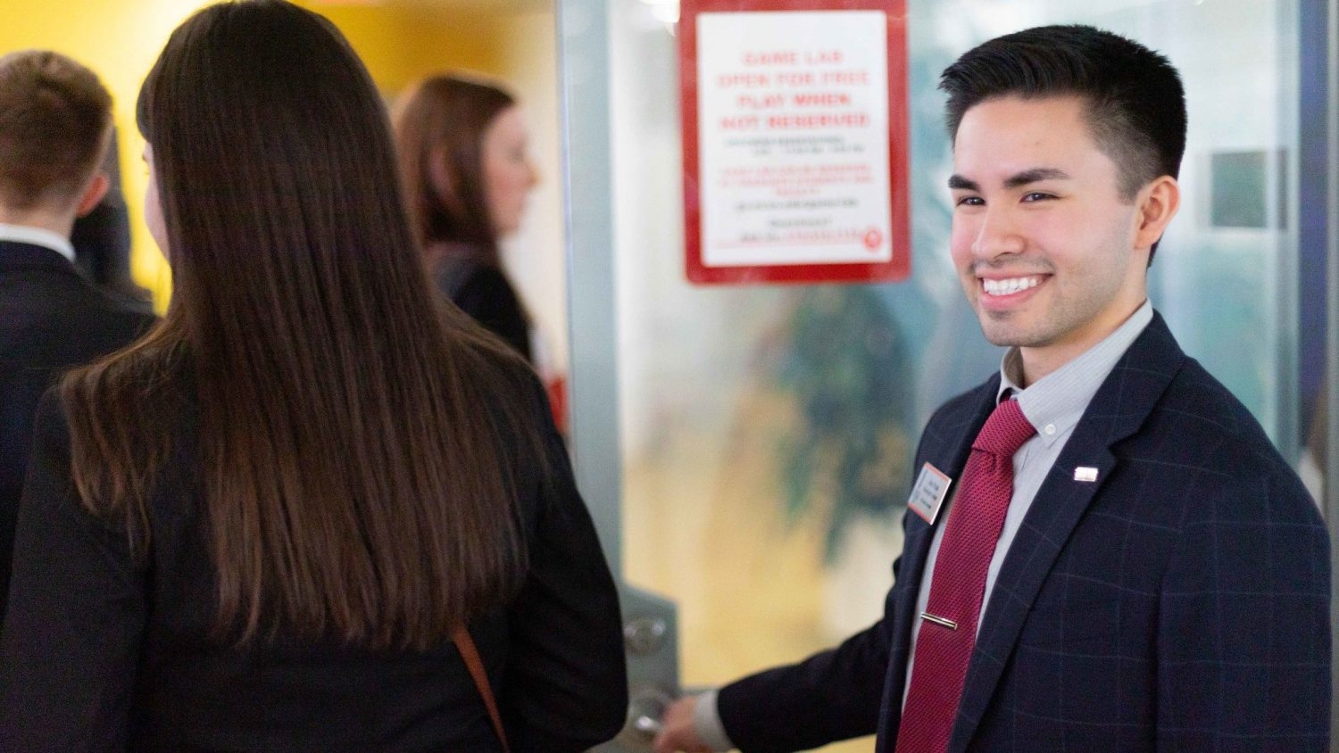 Alex Rojas holding a door for another student