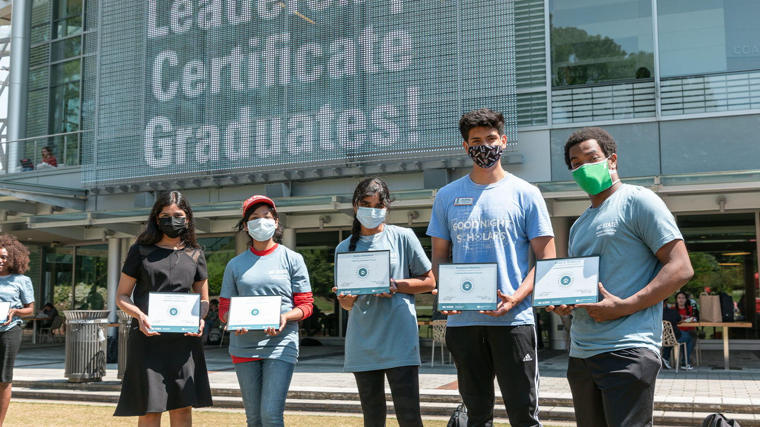 A group of five students holding their certificates for the Leadership Development Program in front of Talley Student Union