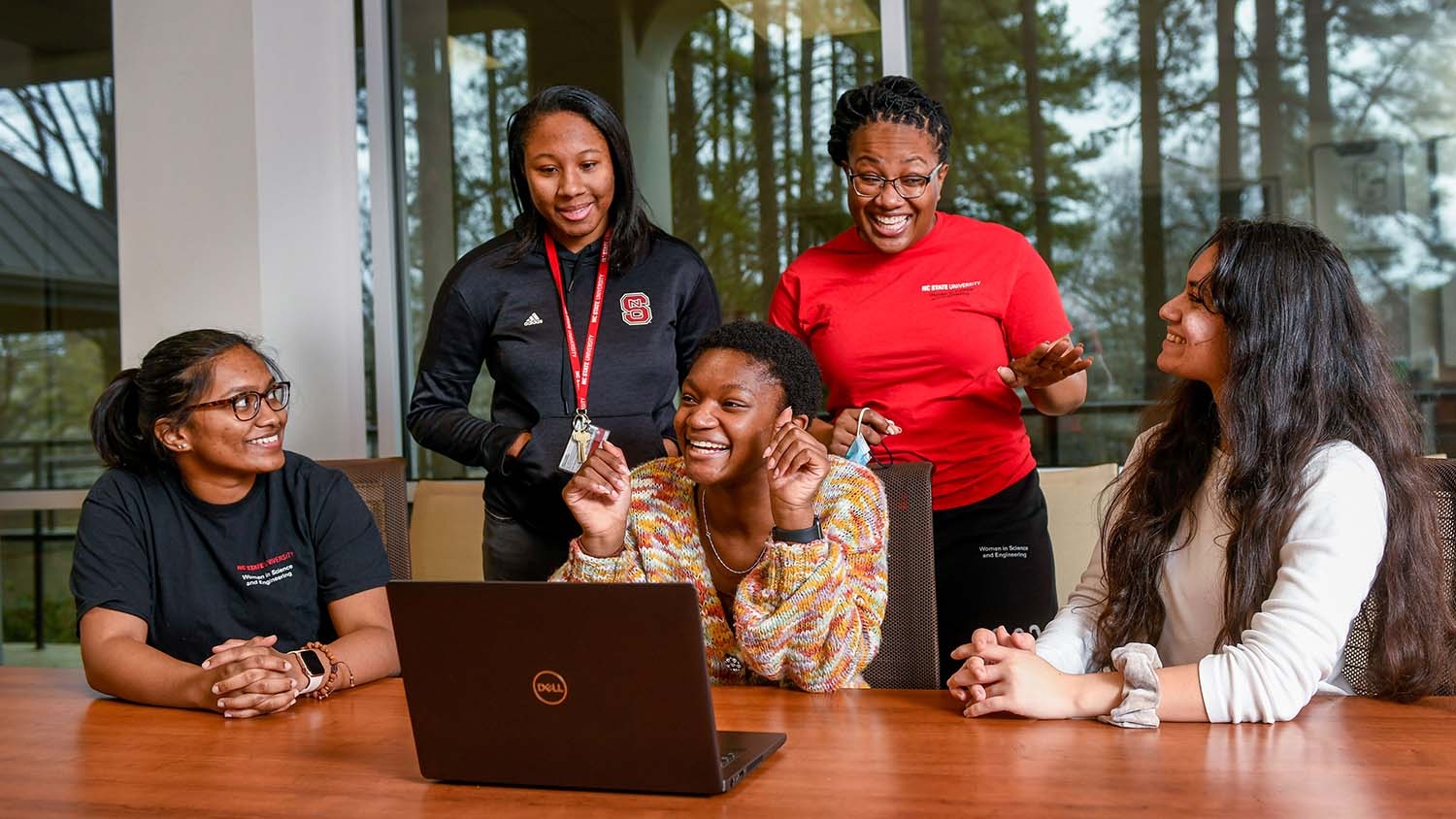 A group of WISE students gathered around a laptop.