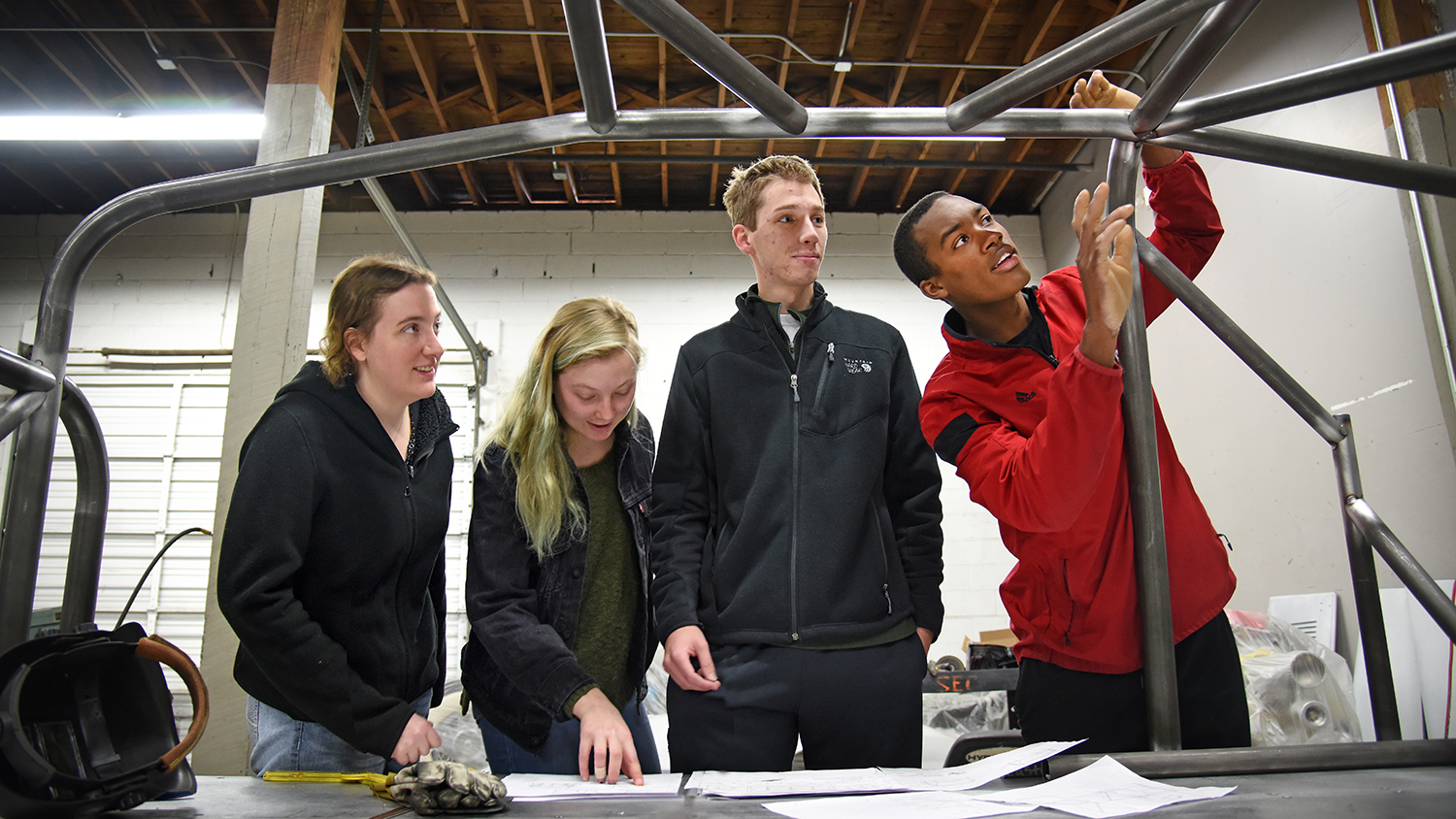 Four students of various genders and ethnicities inspect a scaffolding together.