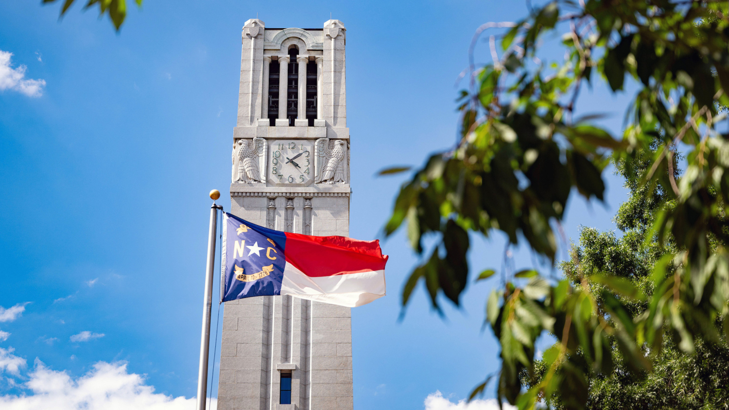 NC State's Memorial Belltower stands in front of a clear summer sky.