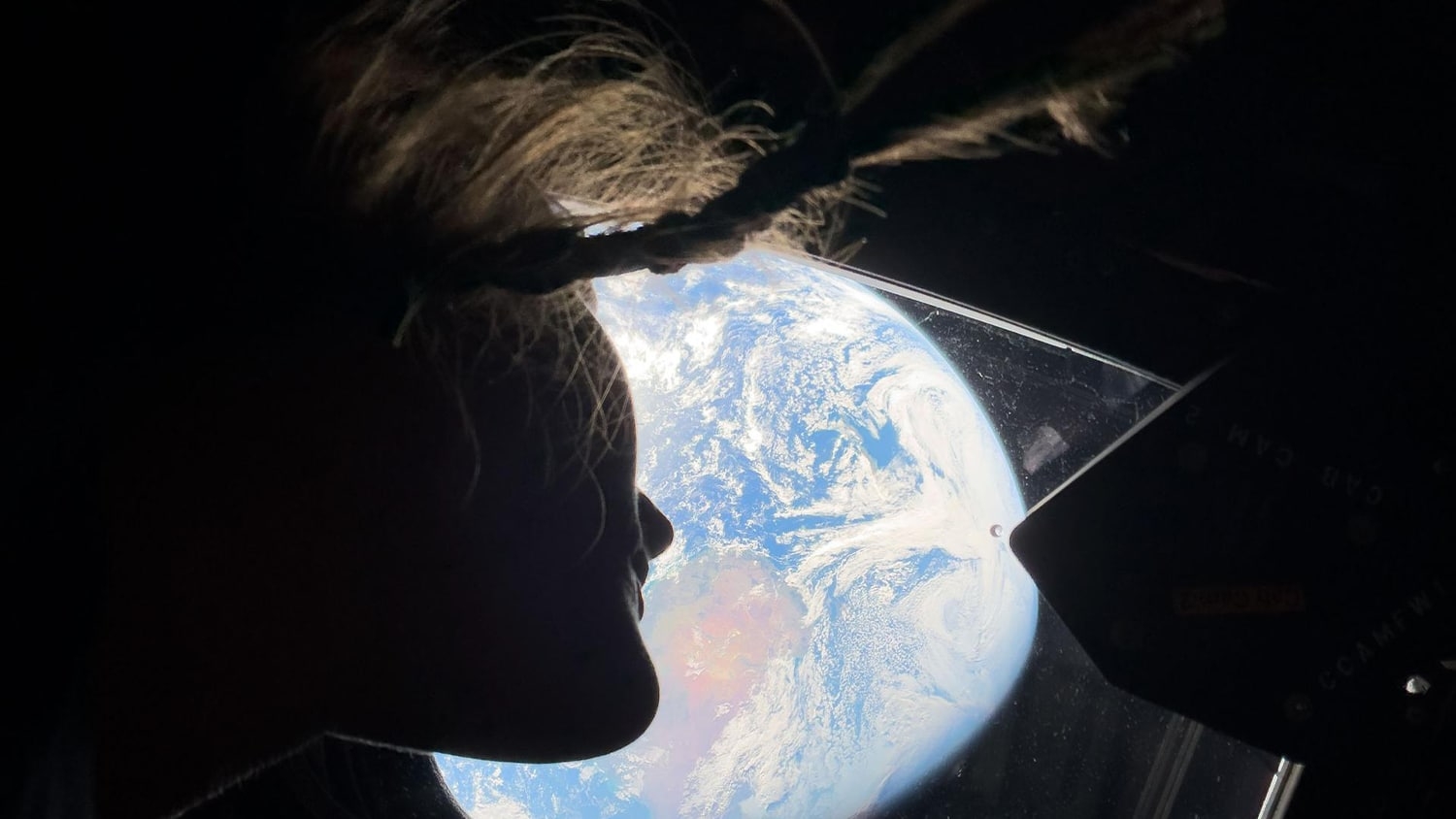 Christina Koch looks down at the Earth from the window of the Orion spacecraft.